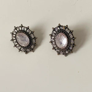 Vintage-inspirerade örhängen med kristaller - Snygga vintage-inspirerade örhängen med en stor oval kristall i mitten omgiven av mindre kristaller. De har en antik silverfärgad bas och mäter cirka 3 cm i diameter. Perfekta för att ge en elegant touch till din outfit.
