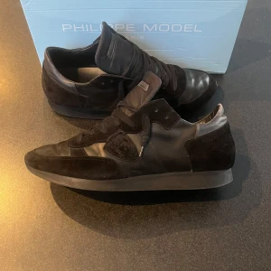 Philippe Model skor, TRPZ - Snygga svarta sneakers från Philippe Model i en kombination av skinn och mocka. Skorna är i storlek 42 men passar också 43. Ljuset på bilden gör så att de ser lite silveraktiga ut, det är dem inte, de är helt svarta. Det finns inte några stora defekter.                    Skick: 8/10   Nypris: ca 4000kr