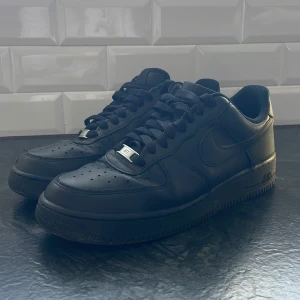 Svarta Nike air force 1  - Otroligt stilrena Svarta Nike air force 1 skor. Väldigt bra pris och mega fint skick 9/10 (finns ett litet håll på högra framsidan av högra skon, syns inte så mycket) 👟 annars är skorna som nya och är 10/10! Nypris 1300kr. Tvättas självklart innan de skickas iväg. Perfekta stilrena skor för en unik och fin look 👀 