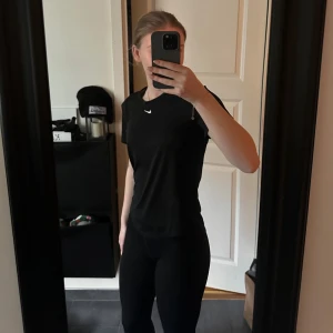 Svart t-shirt från Nike - Säljer en svart t-shirt från Nike med korta ärmar och en liten vit logga på bröstet. Perfekt för träning eller en avslappnad dag💕💕