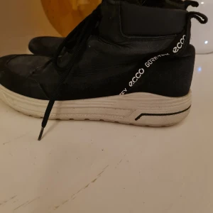 Svarta sneakers från Ecco - Säljer ett par svarta sneakers från Ecco med Gore-Tex teknologi. Skorna har snörning och en vit sula som ger en snygg kontrast. Perfekta för både stad och natur.