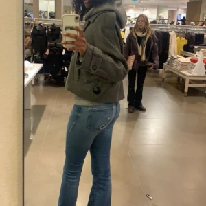 Grå kappa - Säljer en snygg grå kappa och dubbelknäppning. Jackan har en kortare passform och stora knappar framtill. Perfekt för kyligare dagar.