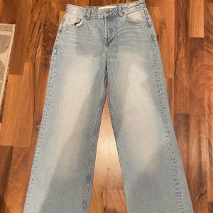 Ljusa jeans från Bershka - Snygga ljusa jeans från Bershka med en avslappnad wide fit. De har en klassisk femficksdesign och knappgylf. Perfekta för en trendig look.