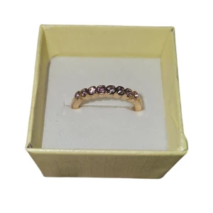 Två eleganta ringar med stenar - Säljer två eleganta ringar, en med lila stenar och en med vita stenar. Båda ringarna har en guldtonad bas och är perfekta för att ge en touch av glamour till din stil. US 6 eller 16.5 mm