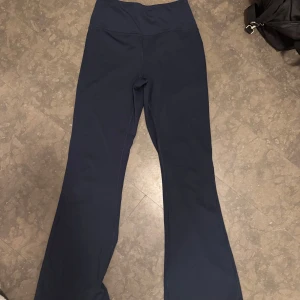 Mörkblå träningsbyxor från SOC - Snygga mörkblå träningsbyxor från SOC med hög midja och bootcut-stil. Tillverkade i ett tekniskt material som andas och håller dig torr under träningen. Perfekta för gymmet eller yoga. Liknar väldigt mycket de trendiga lululemon thights. 