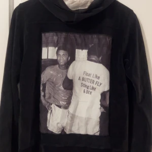 Limitato zip hoddie svart - Snygg svart hoodie från Limitato med ett coolt tryck på baksidan. Text 'Float like a butterfly, sting like a bee'. Hoodien har dragkedja och fickor framtill.