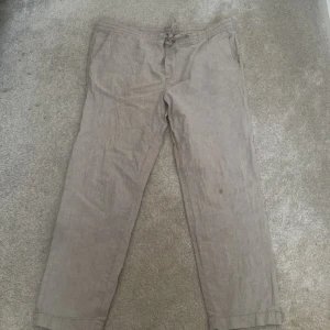 Beige linnebyxor med snörning - Snygga beige linnebyxor med en bekväm passform och snörning i midjan. Perfekta för en avslappnad stil. Tillverkade i en blandning av linne och bomull för en luftig känsla.