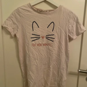 Rosa t-shirt med kattmotiv från Ellos - Säljer en söt rosa t-shirt från Ellos med ett kattmotiv och texten 'Five more minutes'. Perfekt för en avslappnad look.