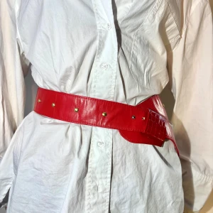 Rött bälte med nitar - Snyggt rött bälte med guldfärgade nitar. Perfekt för att ge en färgklick till din outfit. 💞💞Skärpets fulla längd: 103 cm