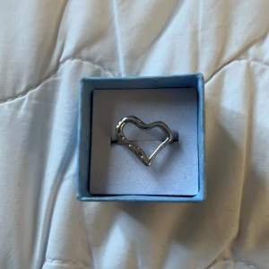 Silverfärgad ring med hjärtdesign från Olympia rings  - Snygg silverfärgad ring med en unik hjärtdesign från Olympia rings. Perfekt för att ge en stilren touch till din outfit. Säljer pgr av att jag bytade till guld