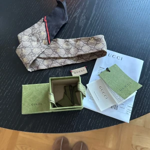 Beige och svart halsduk från Gucci - Scarf från Gucci i väldigt fint skick. Äkthetsbevis och kvitto kommer med samt boxen. Den lilla Gucci lappen tillhör scarfen men klippt av den då den syntes när man hade den i håret så den kommer med. ♥️