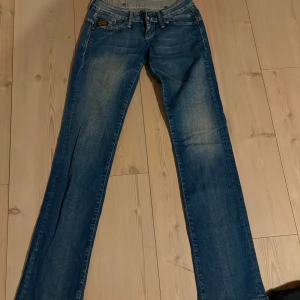 Blå jeans från G-Star - Snygga blå jeans från G-Star med broderad logga på baksidan. De har en klassisk femficksdesign och en bekväm passform. Perfekta för en avslappnad stil.