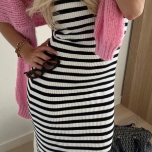 Randig klänning i svart och vit - Snygg och stilren randig klänning i svart och vit. Den har en tight passform och är ärmlös, perfekt för en chic look. Klänningen är ribbad vilket ger en fin struktur och man kan dra upp den som på andra bilden eller ha den längre. Från zara