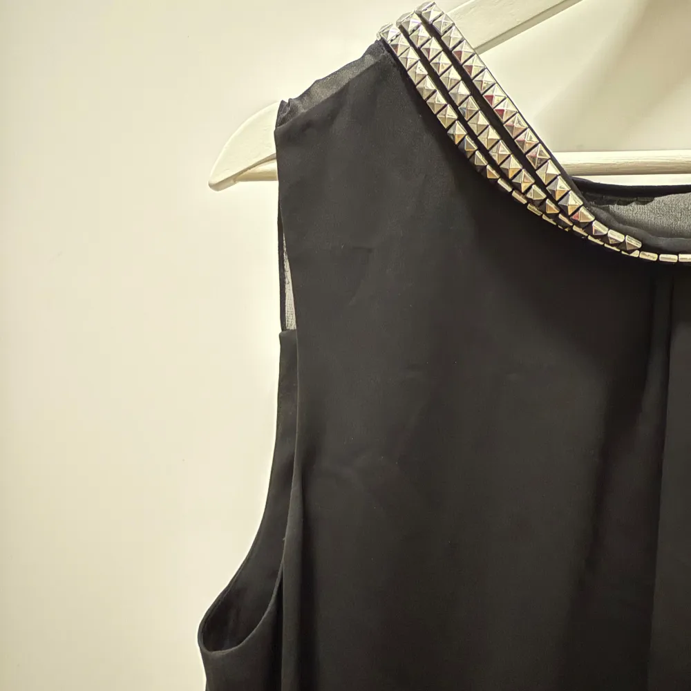 Snygg svart ärmlös blus från By Malene Birger med dekorativa nitar vid halsringningen. Blusen har en enkel och elegant design som passar till många tillfällen! I mycket fint skick! Passar s/m! 🖤. Puserot.