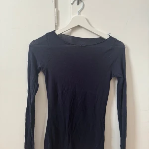 Mörkblå långärmad tröja från intimismi - Säljer en stilren mörkblå långärmad topp från American Apparel. Perfekt för lager-på-lager eller som den är. Toppen har en enkel design med rund hals och är tillverkad i ett mjukt material.