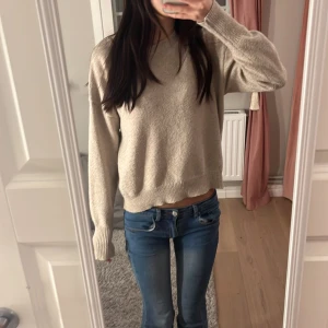 Beige stickad tröja - Mysig beige stickad tröja med långa ärmar. Perfekt för kyligare dagar och enkel att matcha med jeans eller kjol. Tröjan har ribbade muddar vid ärmslut och nederkant för en bekväm passform.🥰
