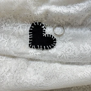 Svart hjärtformat bagcharm / nyckelring - Svart hjärtformad charm med vit söm längs kanterna. Perfekt som en söt accessoar till dina nycklar eller väska. (Vi erbjuder att möta upp i Stockholms innerstad, Huddinge, Tyresö och Lidingö) 