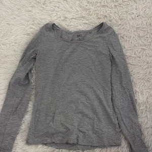 Grå långärmad topp från 157 - Säljer en enkel och stilren grå långärmad topp från 157. Perfekt för lager-på-lager eller att bära som den är. Toppen har en rund halsringning och är tillverkad i ett mjukt material för extra komfort.