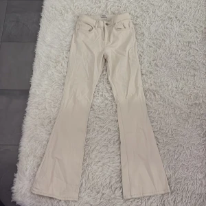 Beige bootcut byxor - Snygga beige bootcut byxor. Perfekta för en stilren look och passar bra till olika tillfällen. De har en knapp och dragkedja framtill.