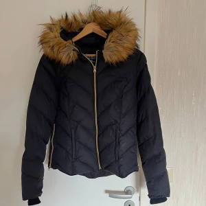 Mörkblå dunjacka från Svea - Säljer en snygg mörkblå dunjacka från Svea med en mysig fuskpäls på huvan. Jackan har en dragkedja i guld och två praktiska fickor med dragkedjor. Perfekt för kalla dagar! 🖤