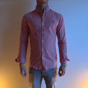 Ralph Lauren Röd och vit rutig skjorta - Snygg röd och vit rutig skjorta med knappar och långärmad design. Perfekt för en stilren look. Skjortan har en klassisk krage och är tillverkad i ett bekvämt material.