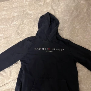 Mörkblå hoodie från Tommy Hilfiger - Säljer en snygg mörkblå hoodie från Tommy Hilfiger. Skicket är 8/10. Ny pris är 800kr, mitt pris är 375kr.