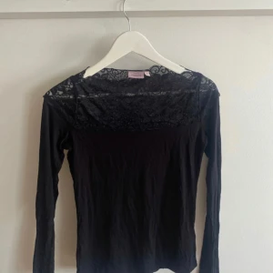 Svart långärmad topp med spets från KappAhl - Snygg svart långärmad topp från KappAhl med jättefin  spetsdetalj vid halsen. Storlek S , använt 2 gånger eftersom tröjan är lite för lång för mig ❤️