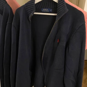 Mörkblå kofta från Polo Ralph Lauren - Säljer en mörkblå zip up från Polo Ralph Lauren som är stickad(ribbad) i man modell. Är i Storlek M och använd men i bra skick. 