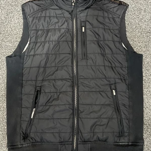 Svart väst från Parajumpers - Snygg svart väst från Parajumpers med dragkedja och flera praktiska fickor. Perfekt för lager-på-lager under kyligare dagar. Västen har en quiltad design och är tillverkad i fleece för extra värme.