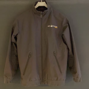 Svart jacka från Sail Racing - Snygg svart jacka från Sail Racing med GORE-TEX-material, 100% vatten och vindtät. Lätt fodrad så passar höst och vår. Storlek 170 cm. Litet hål på baksida arm, se sista bild. Nypris runt 3000kr.