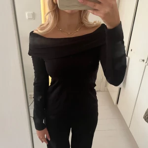 Svart offshoulder topp från Stockh LM Studio - Snygg svart offshoulder topp från Stockh LM Studio. Perfekt för en stilren look med långa ärmar och en elegant passform. Passar utmärkt till både vardag och fest.