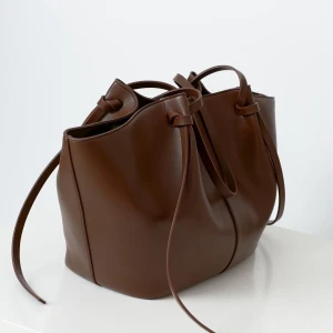 Brun axelväska med gulddetaljer - Snygg brun axelväska i skinn med eleganta gulddetaljer. Väskan har en stilren design med långa axelremmar och använd ett fåtal gånger 