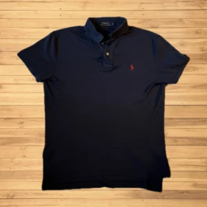 Ralph Lauren Piké - Snygg mörkblå pikétröja från Ralph Lauren med klassisk krage och knappar. Tröjan har en broderad röd logotyp på bröstet. Stilren o skön. Mycket bra skick. Storlek: S. Mvh C.W Closet