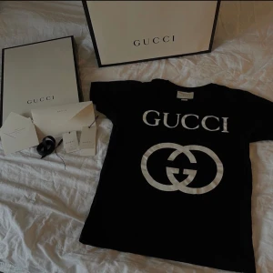 Svart oversized äkta Gucci t-shirt, XS - Äkta Gucci T-shirt, Original pris - 3 500kr  (Använd 2 gånger)                                                             Man får med:  Gucci T-shirt,  Två prislappar, Tack kort, Två kuvert , Svart band med Gucci på  Box + inpackningen och klistermärket,  Gucci påse.                                           XS men är stor i storleken, om man vill ha fler bilder är de bara att säga till 