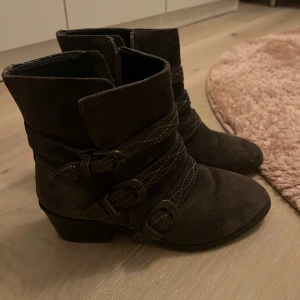 Grå boots med spännen - Snygga låga gråa boots i mocka med tre dekorativa spännen och dragkedja på sidan. Perfekta för höst och vinter !! Om man gillar isabel marant stilen så är dessa skor perfekta 🥰🩷
