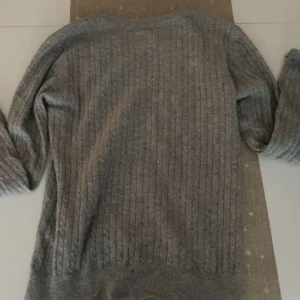 Grå ribbad tröja - Säljer en stilren grå ribbad tröja med långa ärmar. Perfekt för kyligare dagar och enkel att matcha med olika outfits.