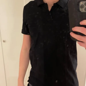 Svart kortärmad pikétröja från Jack & Jones - Snygg svart pikétröja från Jack & Jones med klassisk krage och knappdetalj framtill. Perfekt för en stilren look.