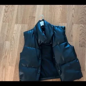 Svart dunväst med dragkedja - Snygg svart skinnväst från Zara! Fint skick