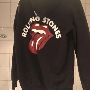 Rollingstones Hoodie storlek S - Svart hoodie med snyggt tryck bak på ryggen. 