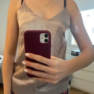 Beige sidenlinne från H&M - Säljer ett elegant beige sidenlinne från H&M med smala axelband och v-ringning. Perfekt för en stilren look. Passar bra till både jeans och kjol.