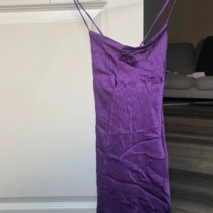 Lila axelbandslös klänning - Säljer en snygg lila klänning med smala band, knytning på ryggen, de är en mini klänning