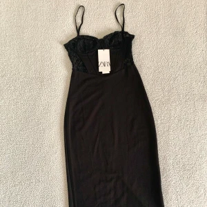 ZARA svart elegant midiklänning med spets - Otroligt snygg midiklänning med slits och spetsdetaljer från ZARA. Smala reglerbara axelband och dold dragkedja i sidan. Ny med prislappar, utan anmärkningar.