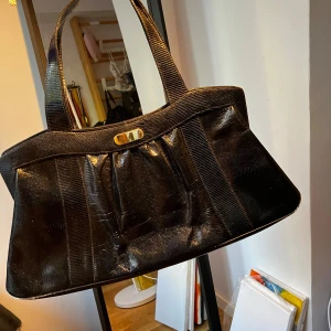 Svart handväska i skinn - Säljer en elegant svart handväska i skinn. Väskan har en stilren design med en praktisk dragkedja och flera fack inuti för enkel organisering. Perfekt för både vardag och fest! Väskan köptes second hand för 300 och är använd Max 2/3 gånger😊