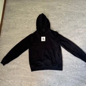 Svart hoodie från Calvin Klein - Säljer en stilren svart hoodie från Calvin Klein. Den har en klassisk design med en stor ficka fram och en liten logga på bröstet. Perfekt för både vardag och chill. Passar till allt och är superbekväm!