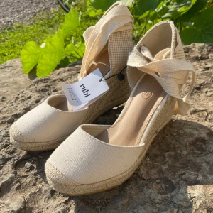 Fina kilklackar från Rubi - Beige färg, låg kilklack, snören för att knyta runt smalbenet. Nyskick. Stl 37. 