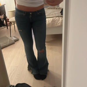 Blå bootcut jeans - Säljer ett par snygga blå bootcut jeans med slitningar på låren. De är lowwaist o stretchiga. Passar mig som har M/36/38 men snyggare på S. Priset kan diskuteras ❤️