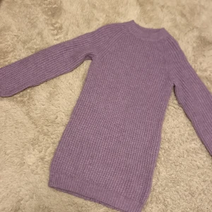 Lila stickad klänning från Cubus - Säljer en mysig lila stickad klänning. har en enkel design med långa ärmar och en rund halsringning. Nästan inte använd