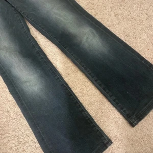 Mörkblå jeans med bootcut - Snygga mörkblå jeans med bootcut-stil och coola slitningar. De har klassiska fem fickor och en knappgylf. Perfekta för en avslappnad look.