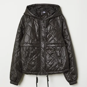 Svart quiltad jacka med huva - Snygg svart quiltad jacka med huva och dragkedja. Jackan har en croppad passform och dragsko i nederkant för justering💗