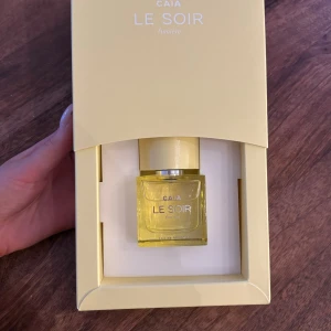 Le Soir Lumière Parfym från CAIA - Elegant parfymflaska i gult från CAIA med doften Le Soir Lumière. Flaskan har en stilren design med en fyrkantig form och en silverfärgad kork. Förpackningen är också gul och matchar flaskans färg.  Nypris-600 säljer den för 500